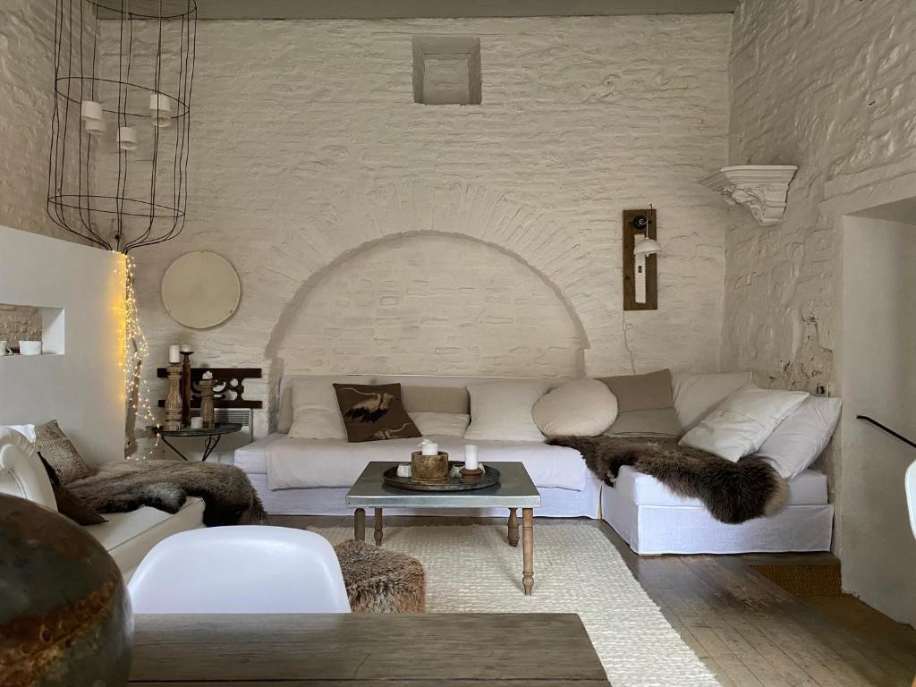 a living room with a white couch and a table at La maison sur la place in Penne-dʼAgenais