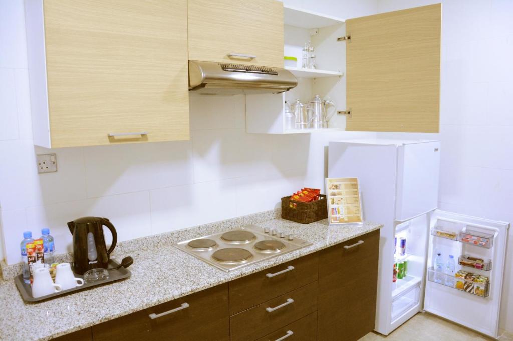 a kitchen with a stove and a white refrigerator at فندق فيفتى ايت السالمية in Kuwait