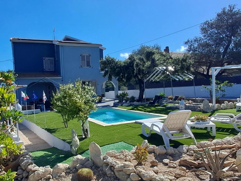 einen Garten mit Pool und ein Haus in der Unterkunft Villa Andres in Sassari
