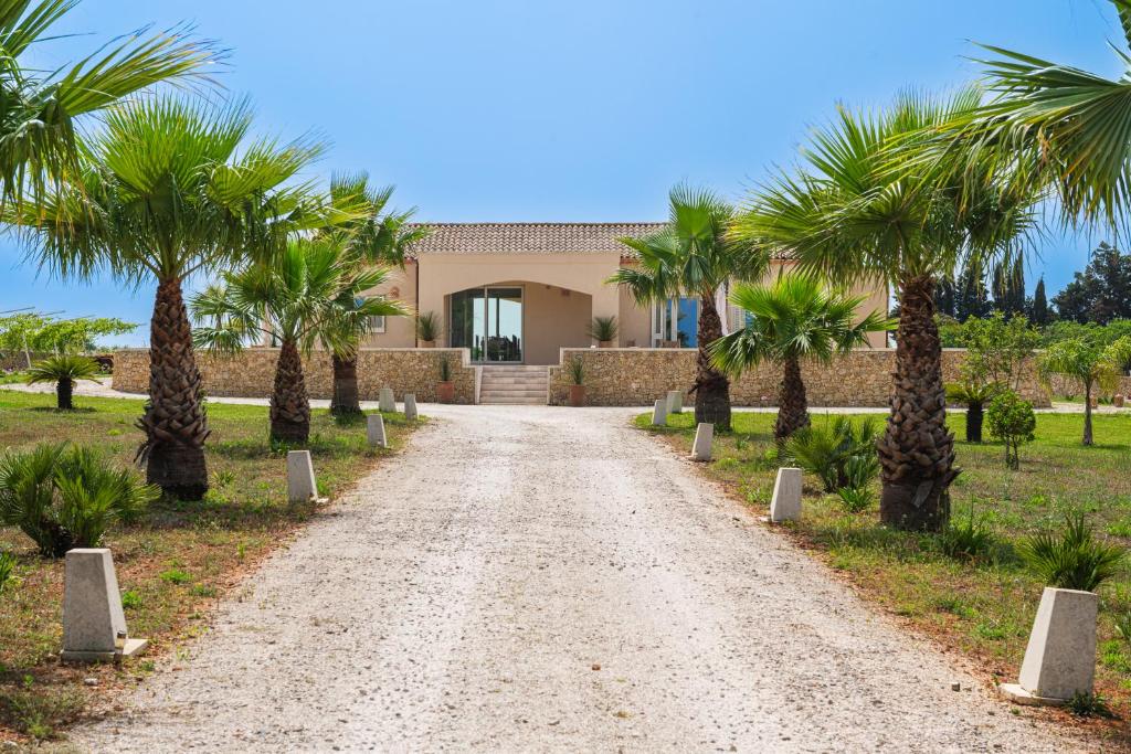 a dirt road with palm trees in front of a house at LA LIMINI in Otranto