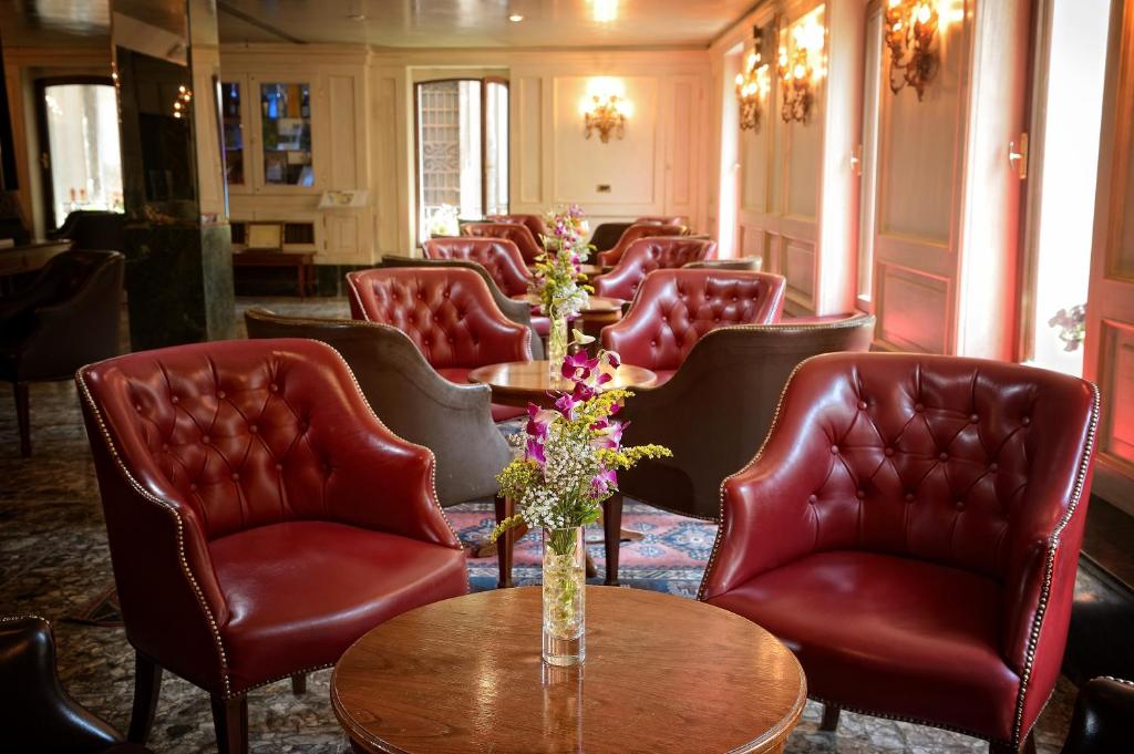 a waiting room with red leather chairs and a table at Albergo Cavalletto &amp; Doge Orseolo in Venice