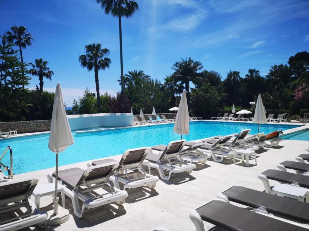 - un groupe de chaises longues et de parasols à côté de la piscine dans l'établissement Studio golfe-juan piscine plage privée tennis, au Golfe-Juan