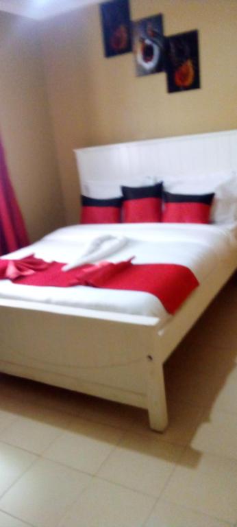 a white bed with red pillows in a bedroom at Best Homestay in Naivasha