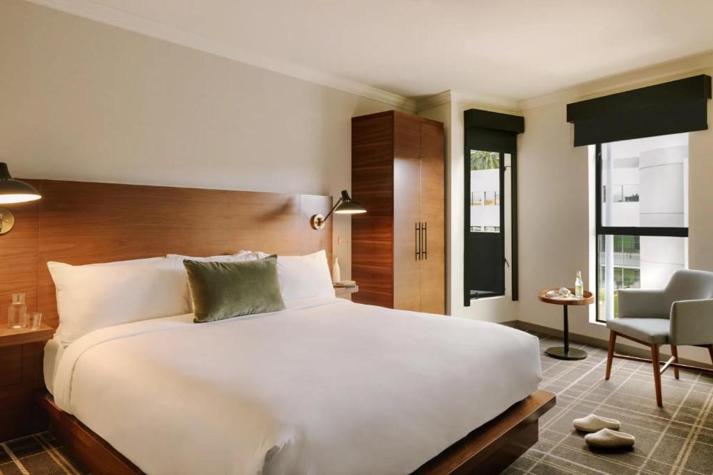 ein Schlafzimmer mit einem großen weißen Bett und einem Stuhl in der Unterkunft FOUND Hotel, Santa Monica in Los Angeles
