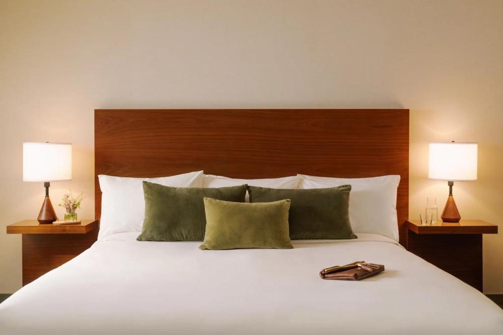 ein Bett mit zwei Lampen und einer Handtasche darauf in der Unterkunft FOUND Hotel, Santa Monica in Los Angeles