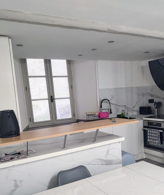 - une cuisine avec un comptoir et 2 fenêtres dans l'établissement T2 centre historique Briançon, à Briançon
