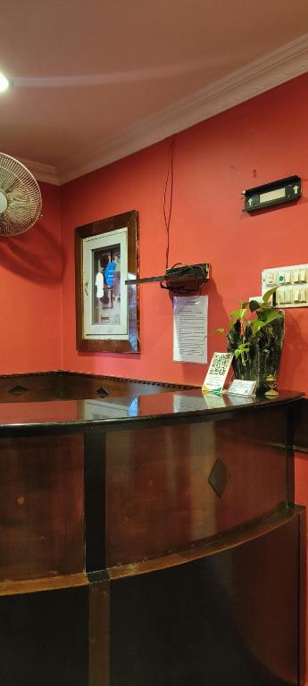 a red wall with a desk and a mirror at Comfort Rooms and Dormitory in Trivandrum