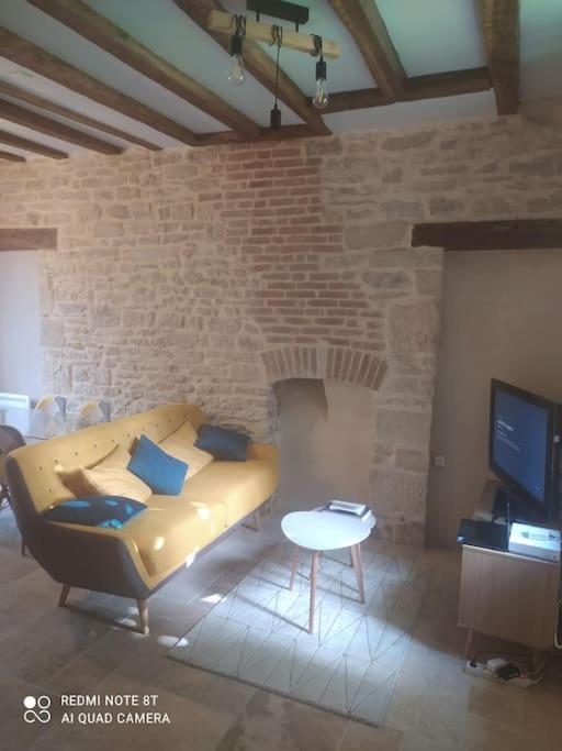 un salon avec un canapé et un mur de briques dans l'établissement Charmant Appartement 2 pièces avec extérieur, à Dijon