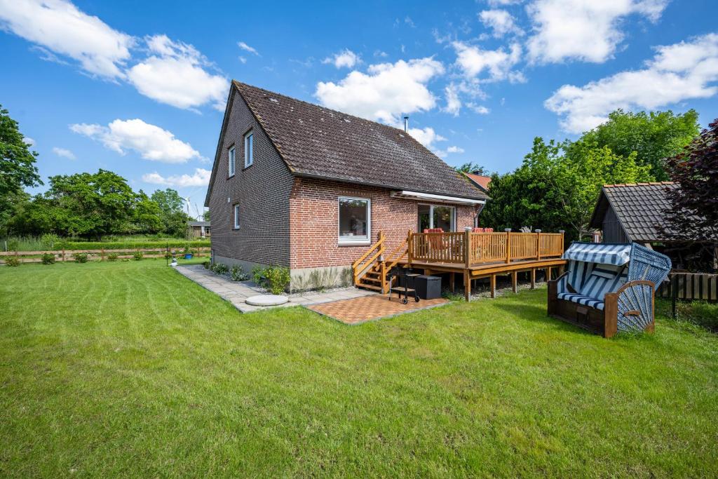 uma pequena casa com um deque e um quintal em Ferienhaus Ostseetraum em Göhl