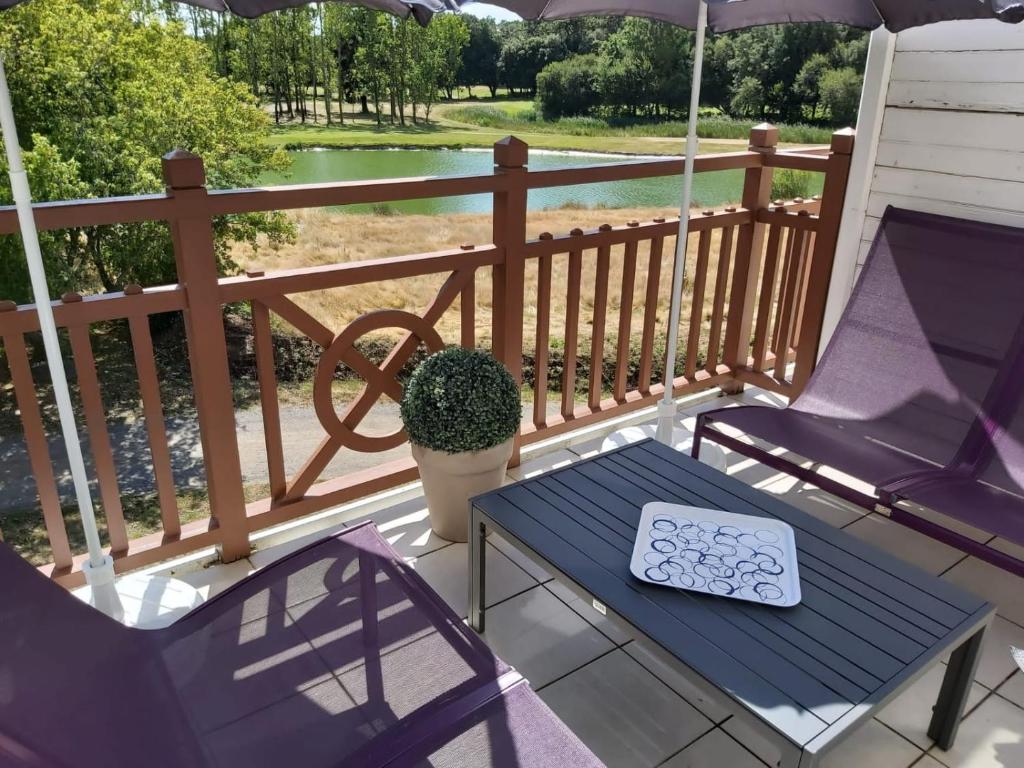 - une terrasse couverte avec 2 chaises, une table et un parasol dans l'établissement Superbe vue sur le golf, à Talmont-Saint-Hilaire