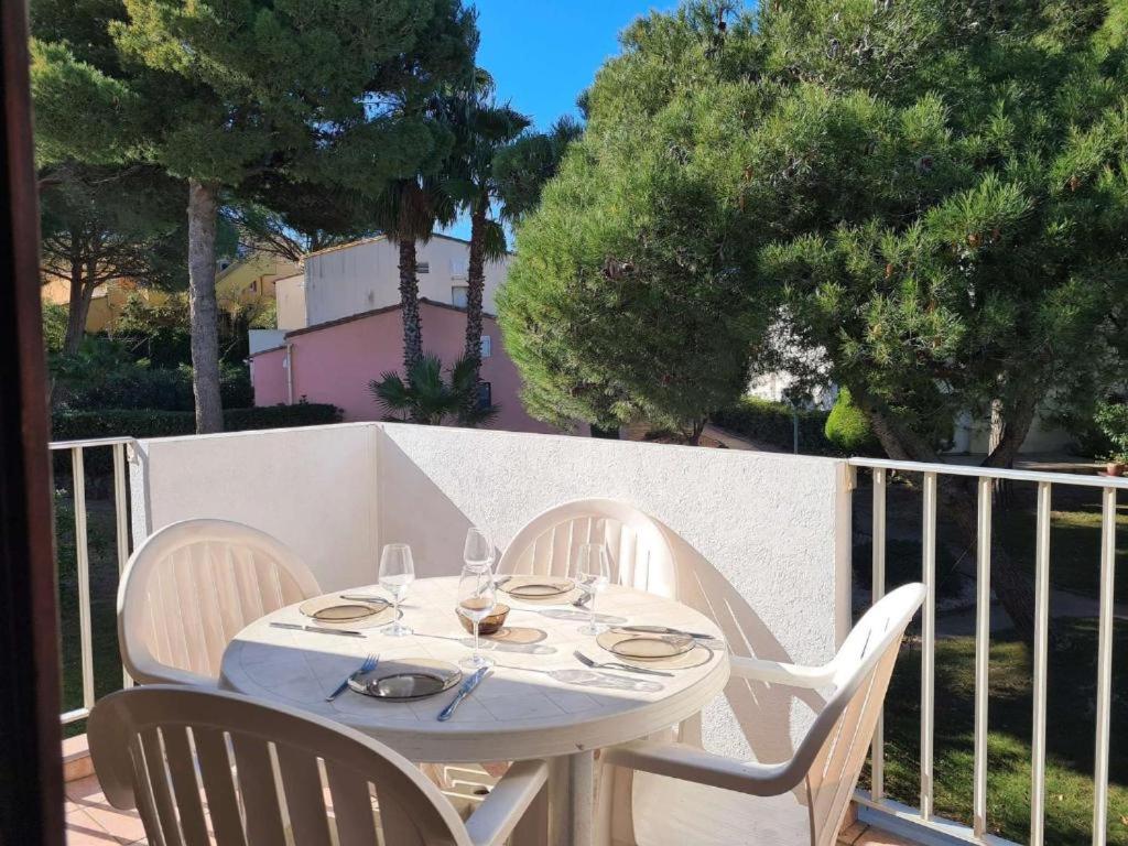 une table blanche et des chaises sur un balcon dans l'établissement La Rouquille Cap d'Agde,, au Cap d'Agde