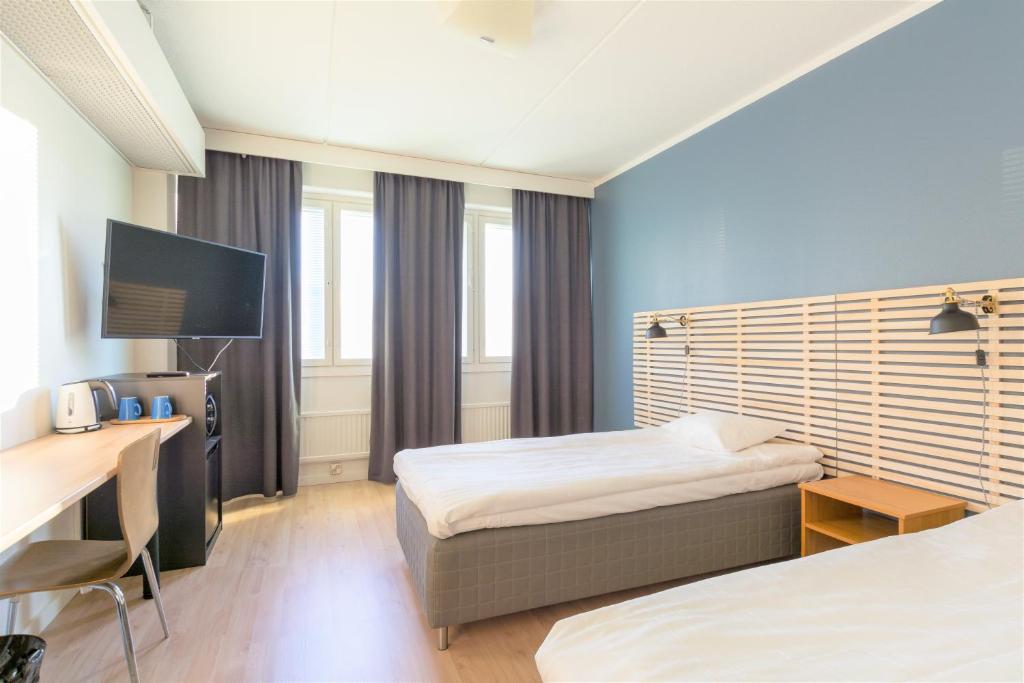 um quarto de hotel com duas camas e uma secretária em Torget Aparthotel em Pori