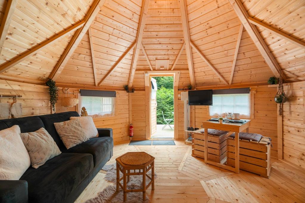 un soggiorno con divano in una cabina di legno di Gite Petite Chaumière Kota finland a Plurien