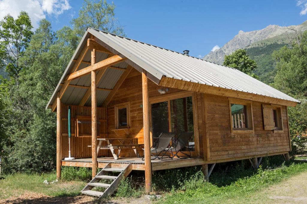 uma cabana de madeira com um telhado de metal em Huttopia Vallouise em Vallouise