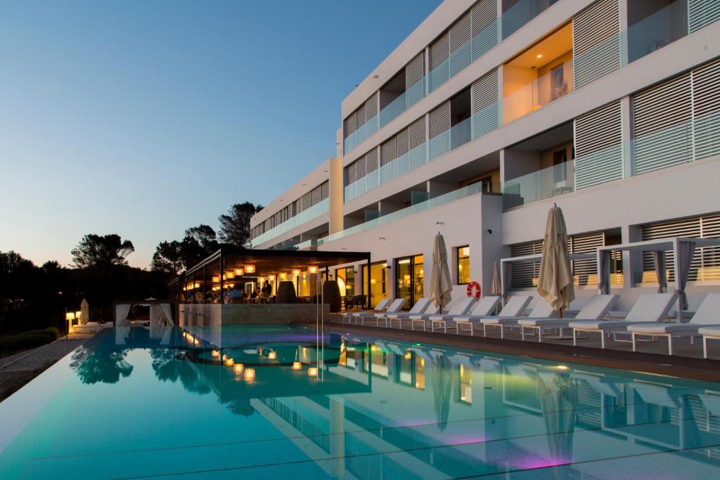 um hotel com piscina e espreguiçadeiras em Hotel Cala Saona & Spa em Cala Saona