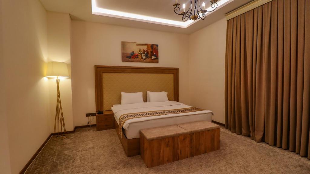 - une chambre avec un lit, une table et une lampe dans l'établissement Haden Hotel, à Erbil