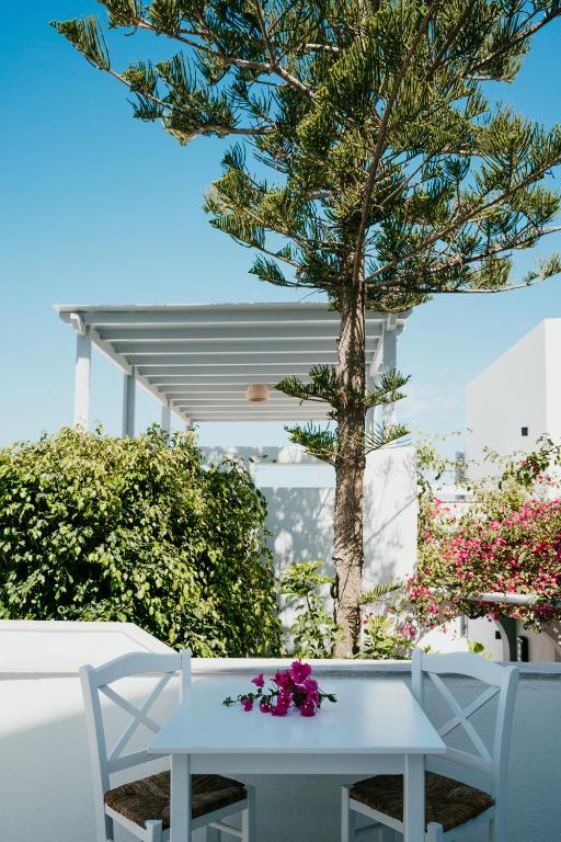 un tavolo bianco con sedie e fiori di Sunrise Paros a Naoussa