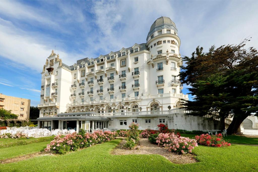 een groot wit gebouw met bloemen ervoor bij Eurostars Hotel Real in Santander