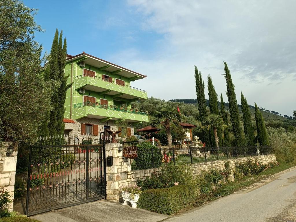 een groen gebouw met een hek en bomen bij Villa Solitude in Berat