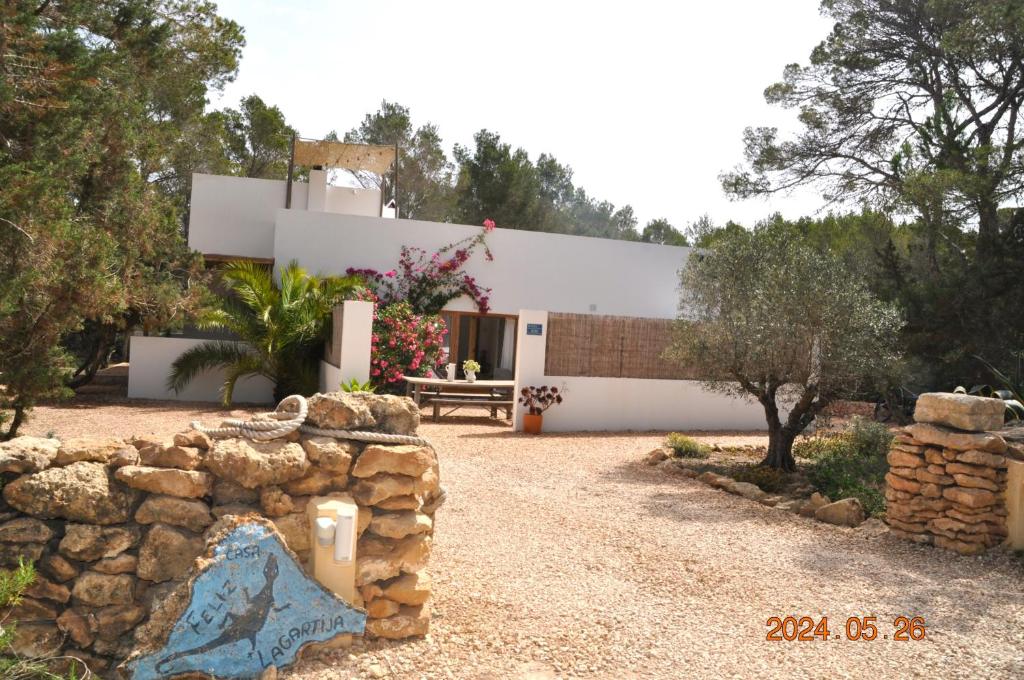 una casa con un muro di pietra di fronte di Feliz Lagartija a Cala Saona