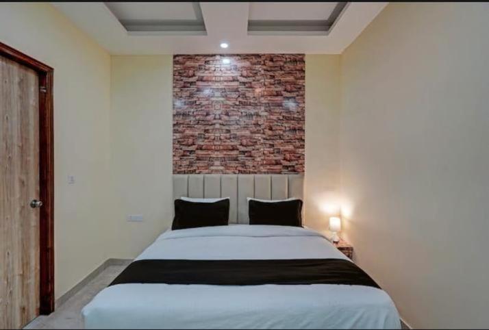 1 dormitorio con 1 cama grande y pared de ladrillo en icyhotels ADA residency and confrence centre, en Noida