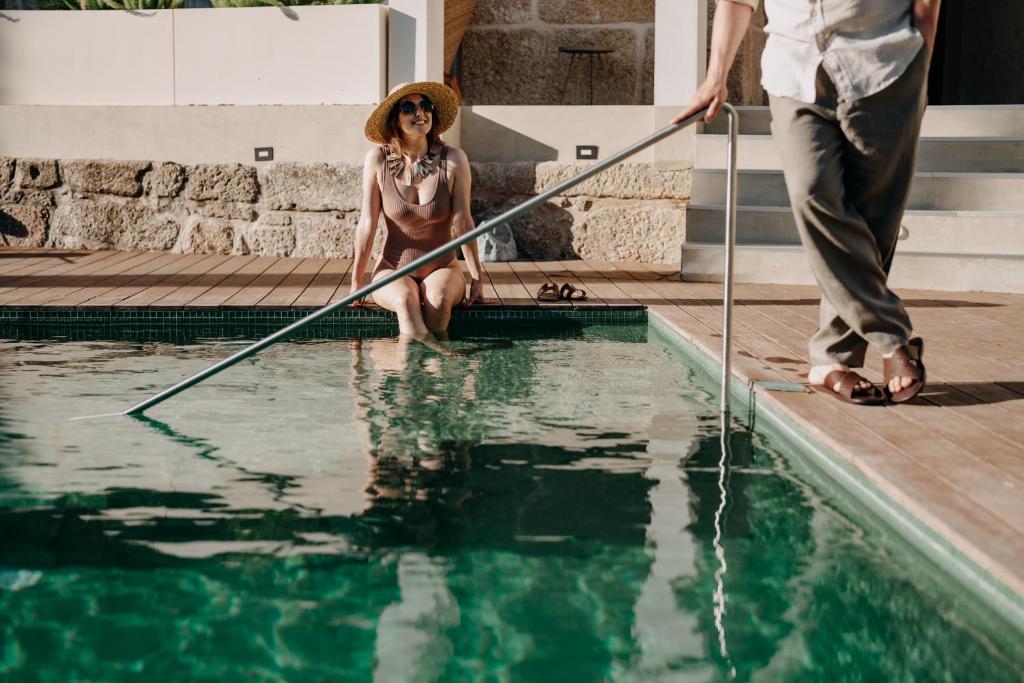 un hombre y una mujer sentados junto a una piscina en Casa das Lérias, en Amarante