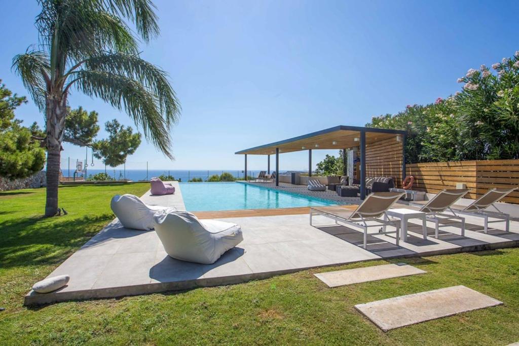 a swimming pool with lounge chairs and a swimming pool at RLM Prime Beach Panoramic Villa in Kolymbia
