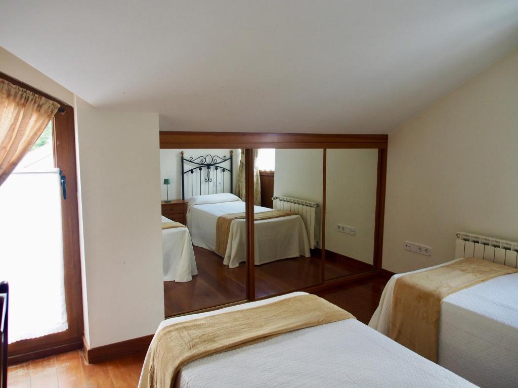 a hotel room with two beds and a mirror at Apartamento Remoña 2 in Espinama