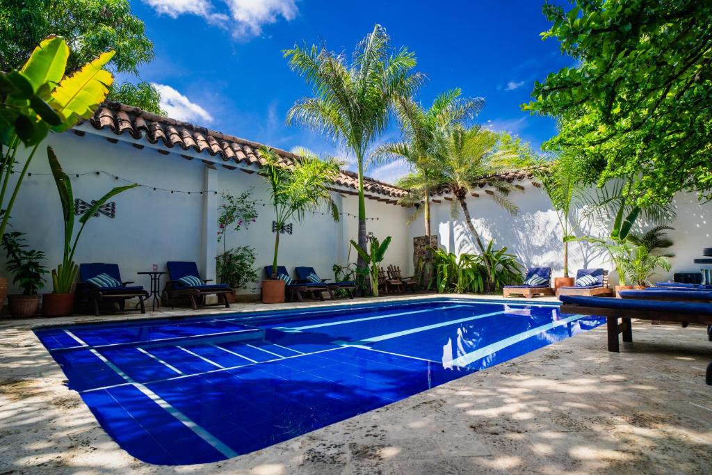 a swimming pool in front of a house with palm trees at Hotel Boutique Al Alma in Santa Fe de Antioquia