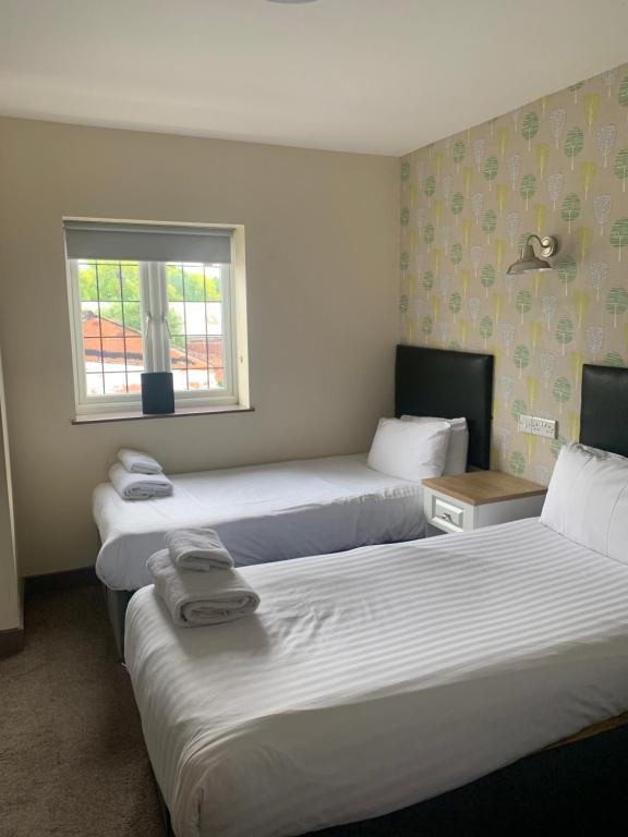 a hotel room with three beds and a window at The Bournbrook Inn in Birmingham