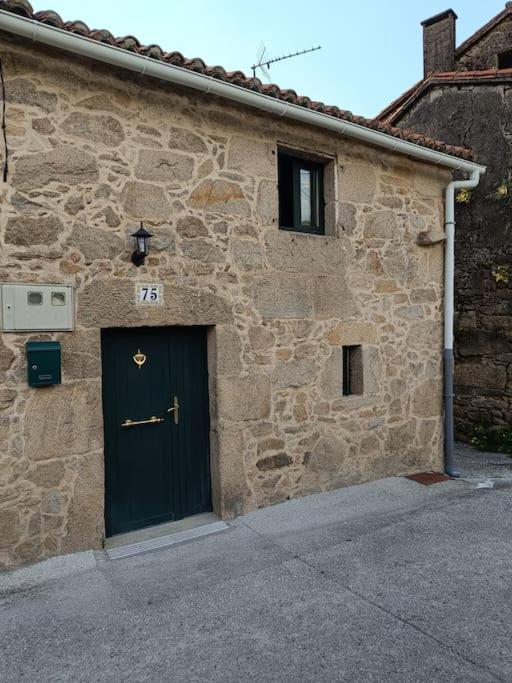 a stone building with a black door at A Casiña de Arretén in Padrón