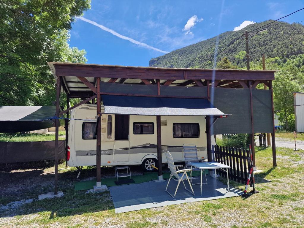 吉洛梅Magnifique grande Caravane aux Gorges de Daluis的一辆带遮阳篷的露营车，前面有一张桌子和一张野餐桌