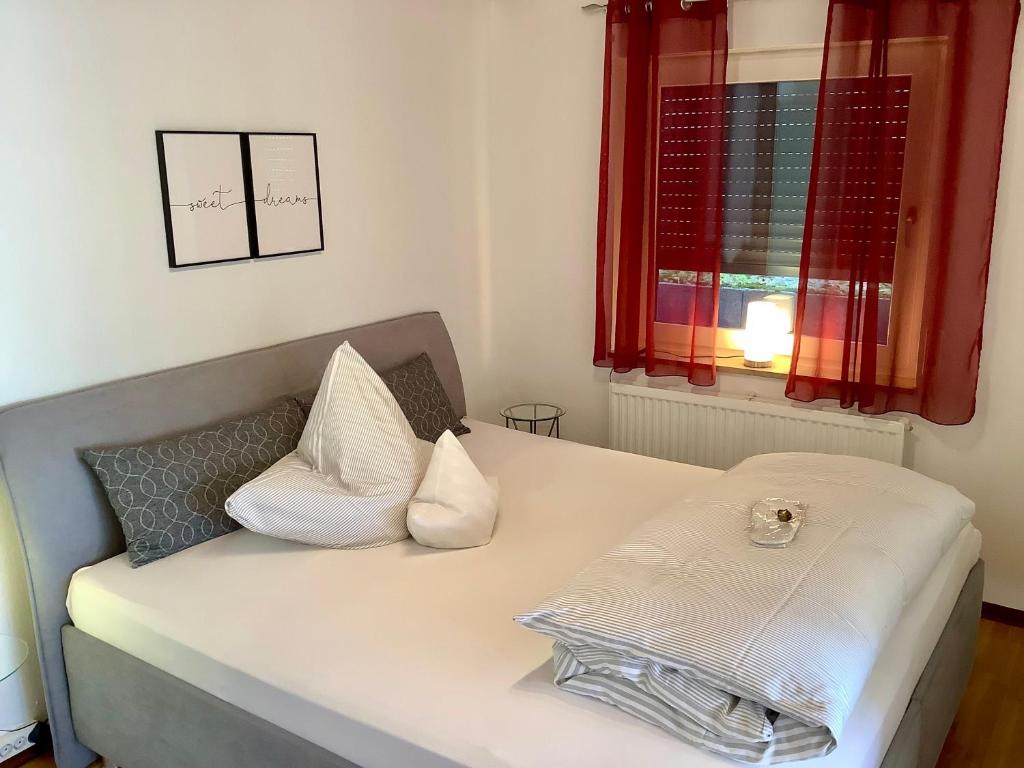 ein Schlafzimmer mit einem Bett mit weißen Kissen und einem Fenster in der Unterkunft Appartement 51 in Schwäbisch Hall