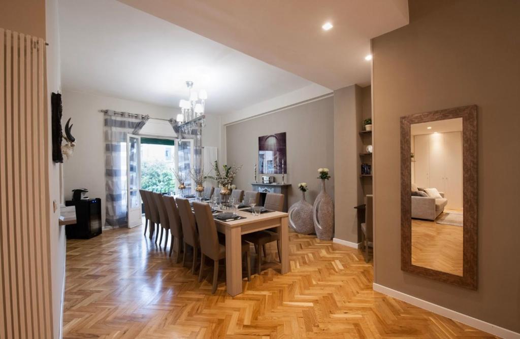Dining room with long table, chairs, chandelier, large window with curtains, wooden parquet floor