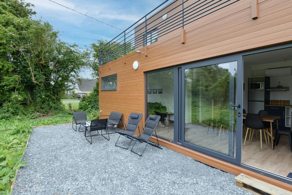 a group of chairs sitting on a patio next to a building at Le D-Day - Sauna - A moins de 2 km de la plage in Sainte-Honorine-des-Pertes