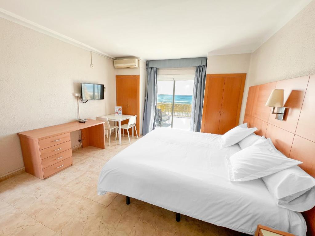 Un dormitorio con una gran cama blanca y un escritorio. en Aparthotel Solifemar, en Castelldefels
