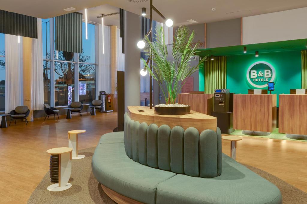a lobby with a couch with a plant in the middle at B&B HOTEL Barcelona Viladecans in Viladecáns