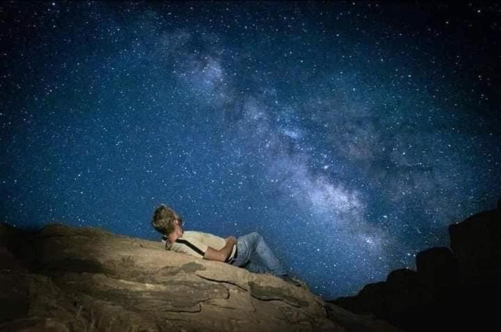 um homem deitado numa rocha sob um céu estrelado em Bedouin bunch camp em Wadi Rum