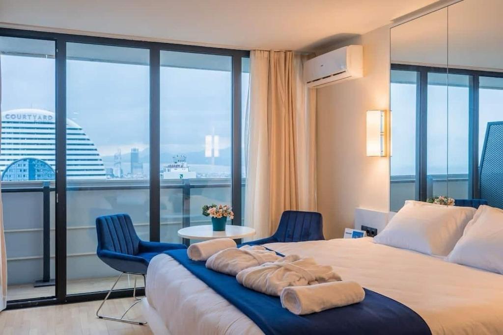 a bedroom with a large bed with two blue chairs at Orbi City Hotel VIP - Batumi in Batumi