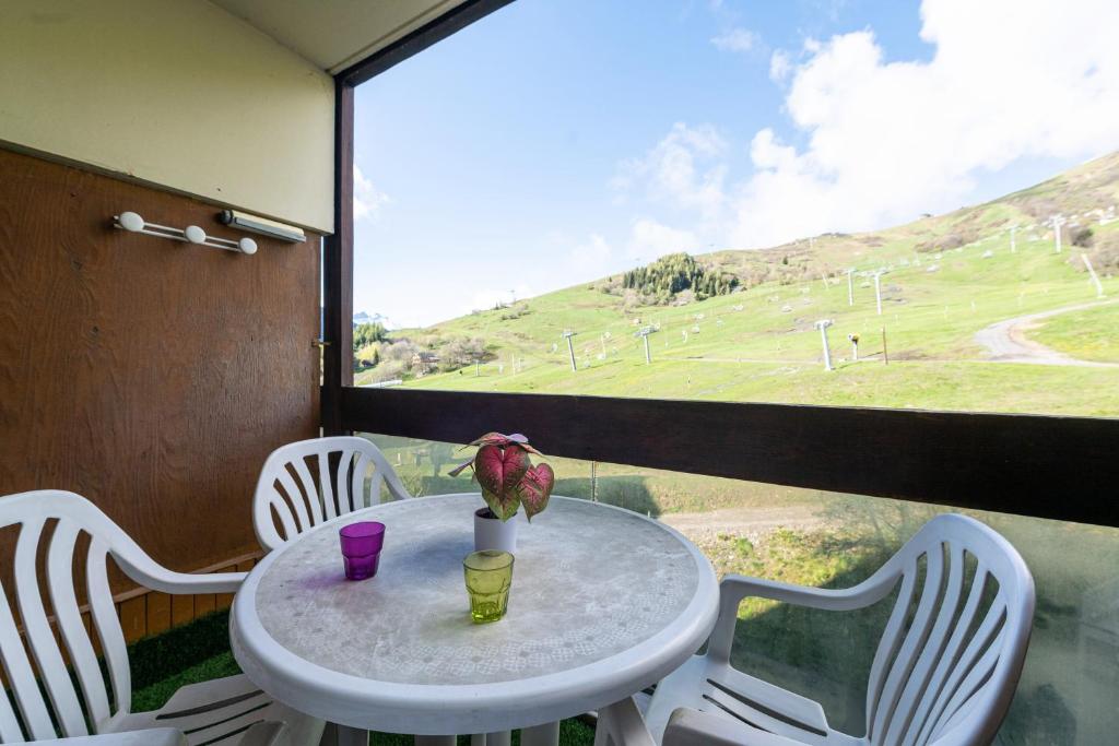 un tavolo con un vaso di fiori e una vista su un campo di Le Cosmos Villarembert - Studio 5p vue montagne a Villarembert