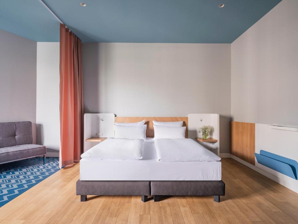 a bedroom with a large white bed and a couch at Numa Berlin Kudamm in Berlin