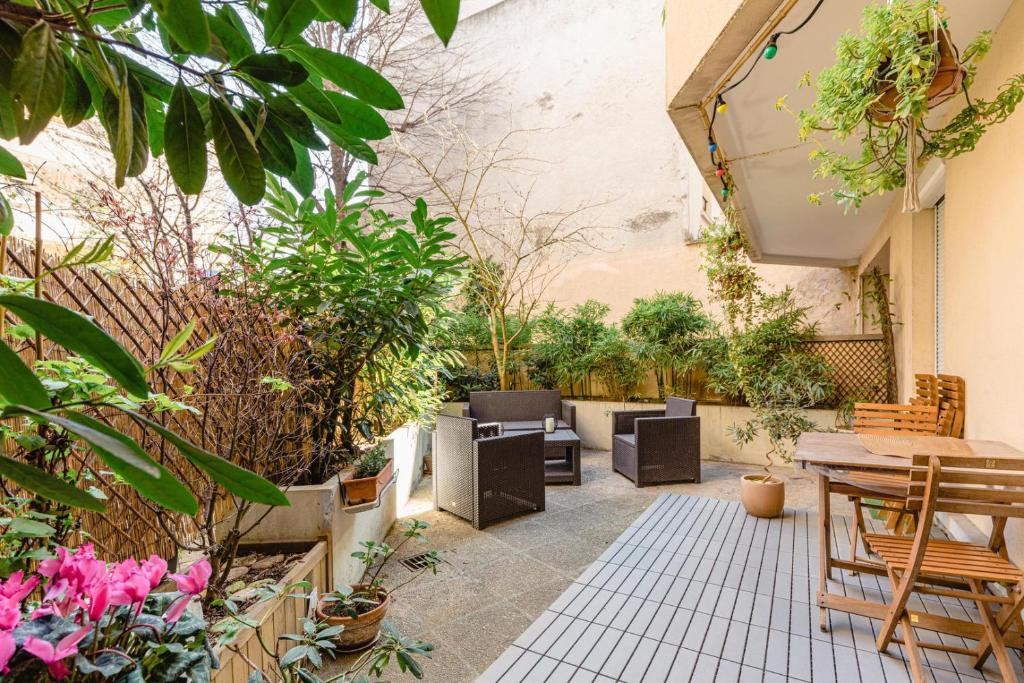 un patio con mesas, sillas y plantas en GuestReady - Sunlit stay near Père-Lachaise, en París