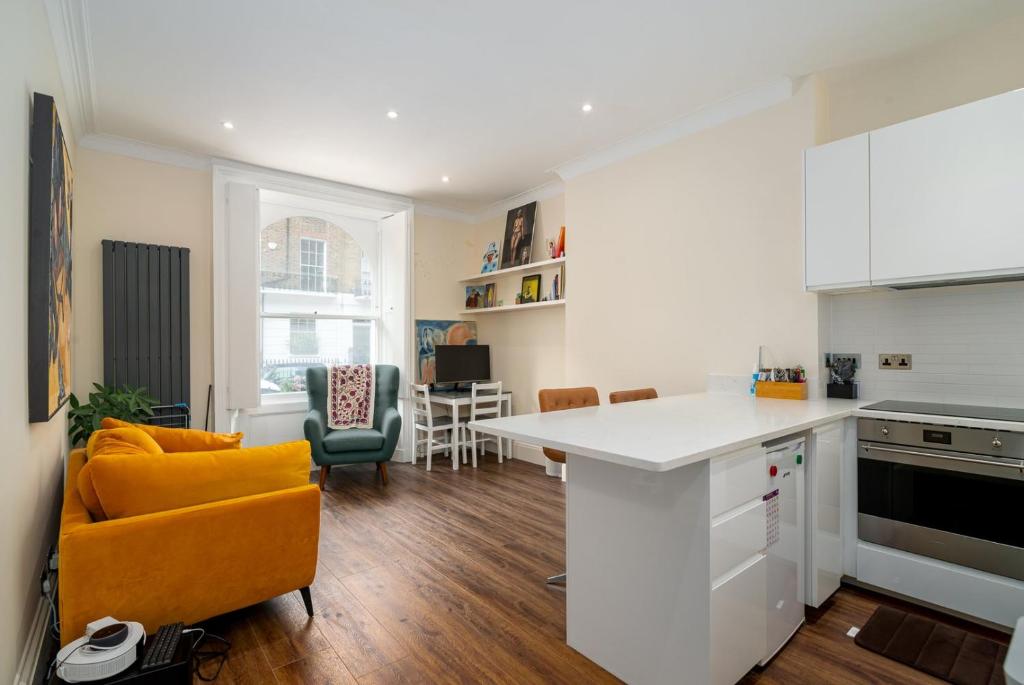 uma cozinha com um balcão branco e uma cadeira laranja em GuestReady - Fantastic Apt near Regent's Park em Londres