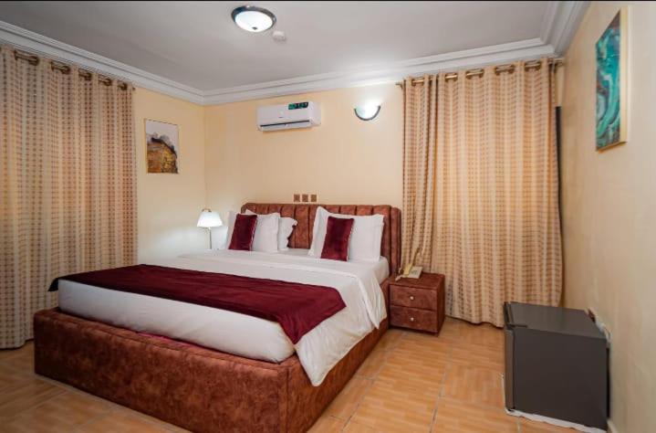 Checkers Suite & Apartments في أبوجا: غرفة نوم بسرير كبير وتلفزيون