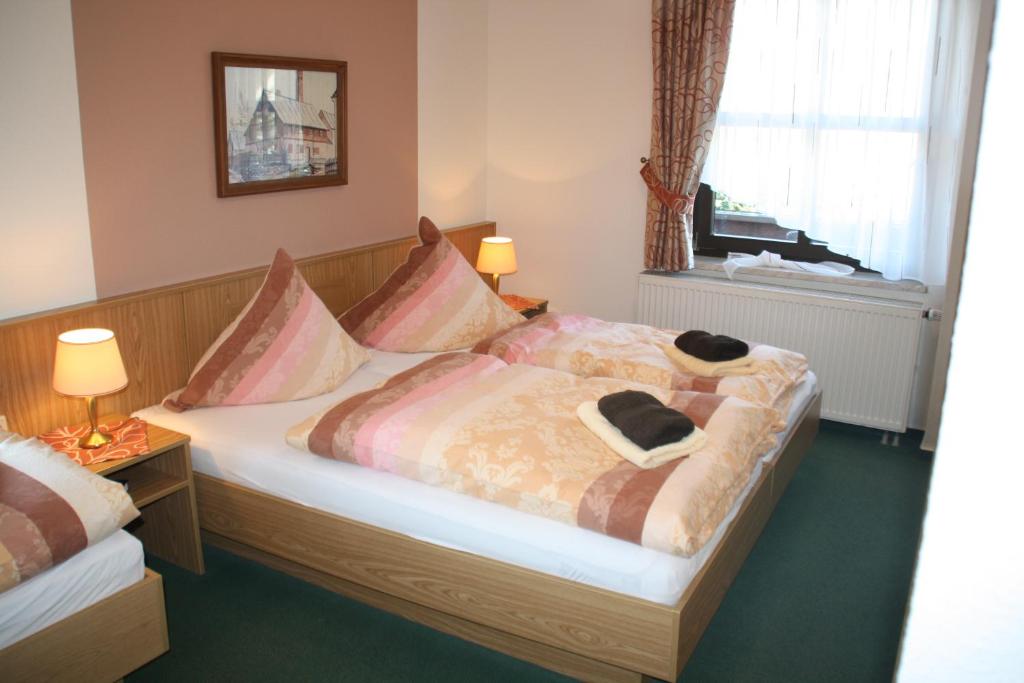 Un dormitorio con una cama con dos sombreros. en Hotel-Pension Flechsig, en Hartmannsdorf
