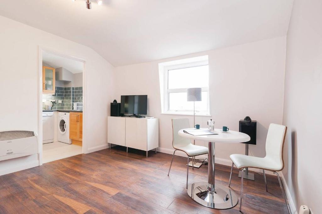 a white room with a table and chairs and a kitchen at GuestReady - Cityscape Retreat near The Shard in London