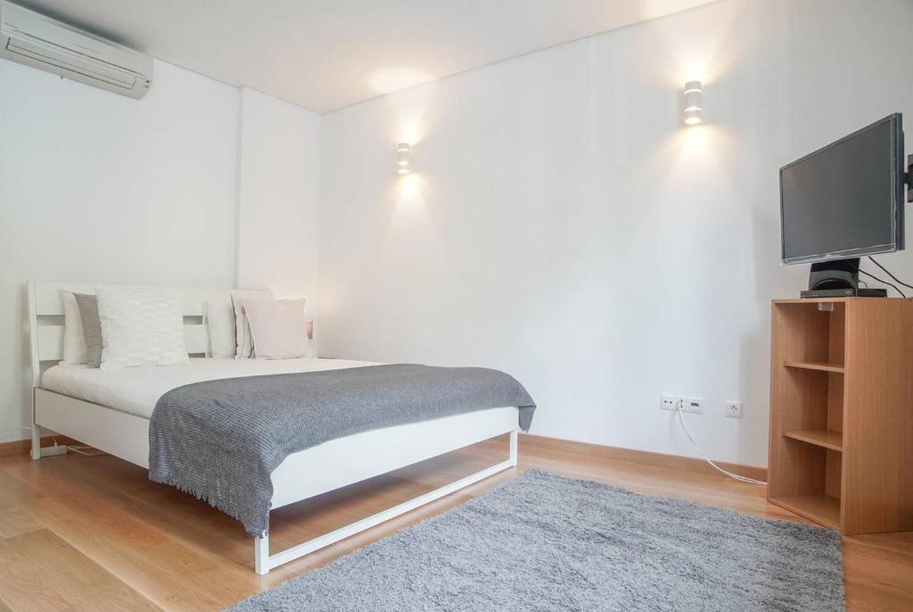 a bedroom with a bed and a flat screen tv at GuestReady - Spacious and Modern Studio in Belém! in Lisbon