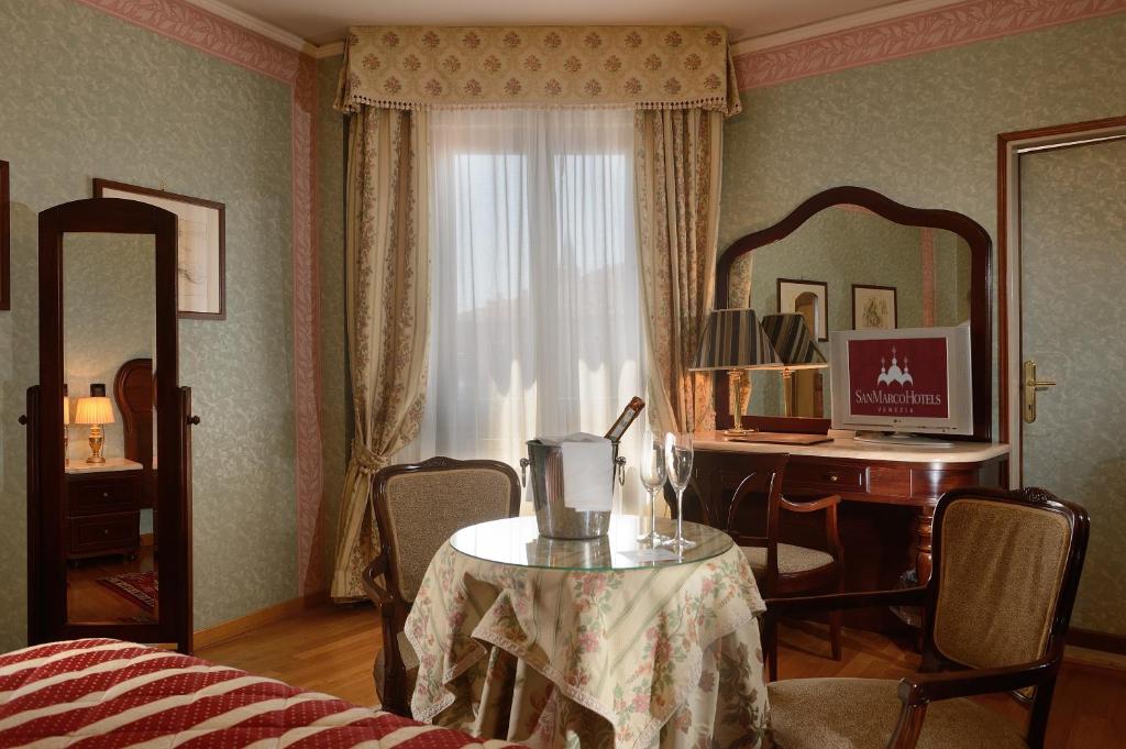 a bedroom with a table and a desk and a window at Albergo Cavalletto &amp; Doge Orseolo in Venice