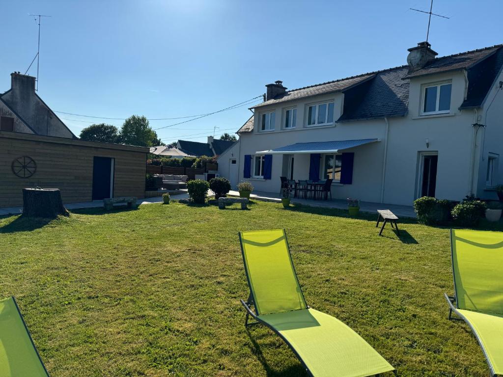 une cour avec 2 chaises longues et une maison dans l'établissement Villa Ty PY : Charme moderne et tranquillité, à Fouesnant