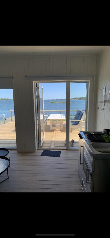 a kitchen with an open door to a patio with the ocean at Bryggstuga med privat bastu in Norrtälje